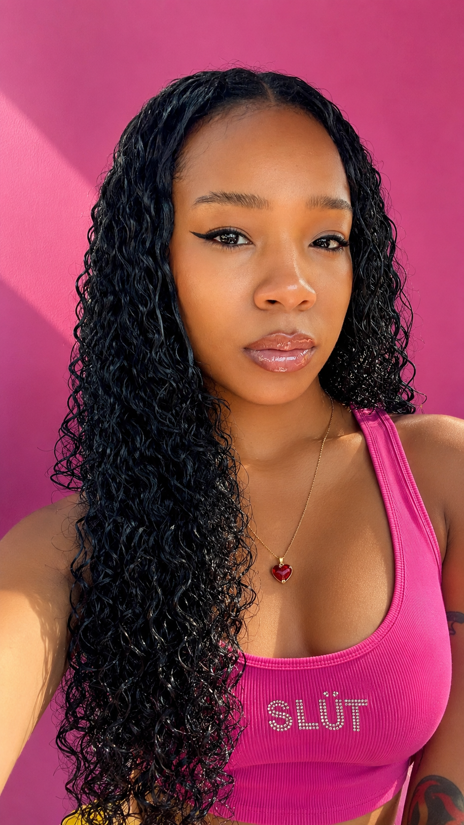 SoysauceSani portrait against a pink wall in a SLUT bralette