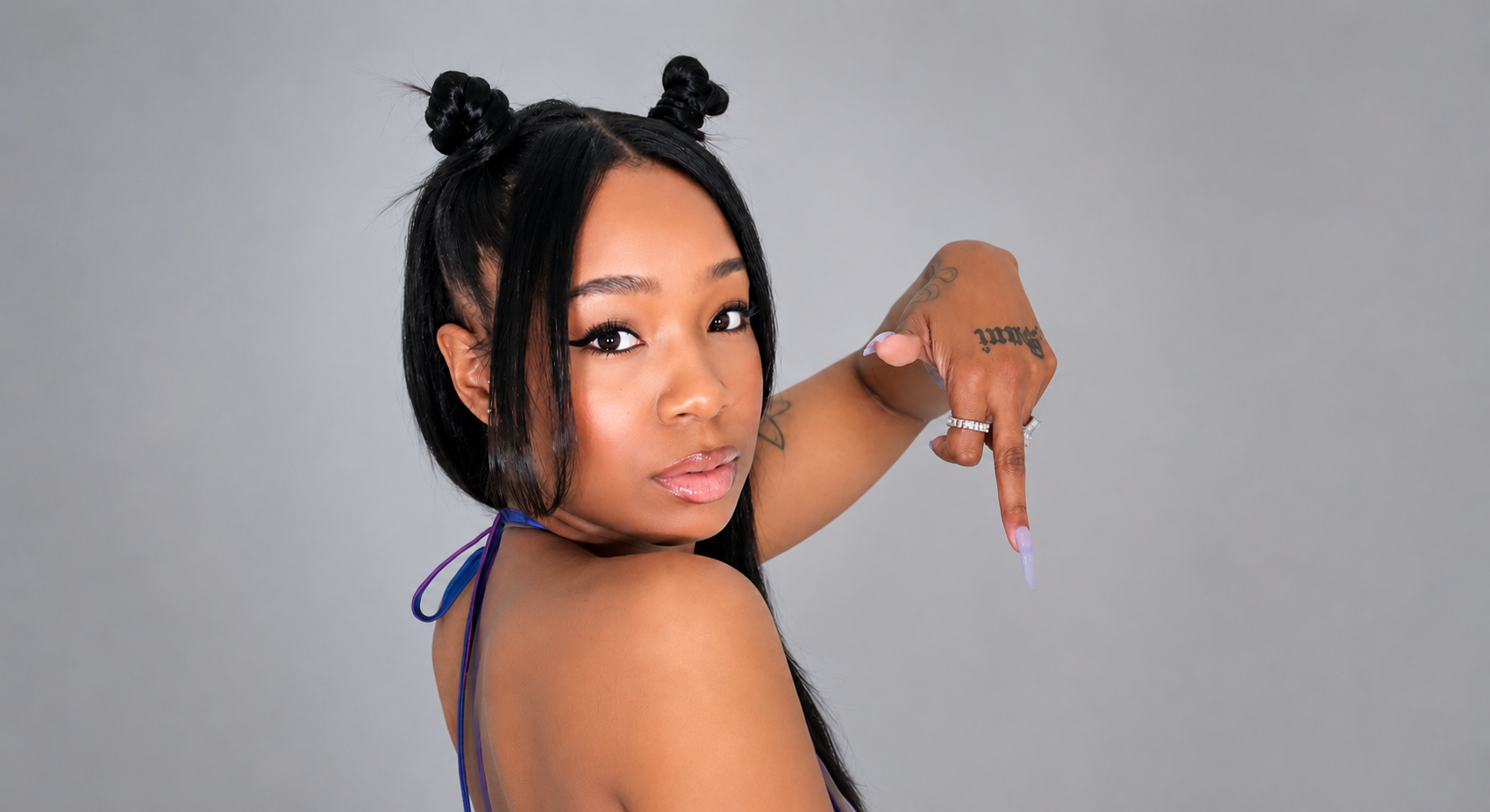 SoysauceSani in a studio portrait with space buns and a purple SLUT top